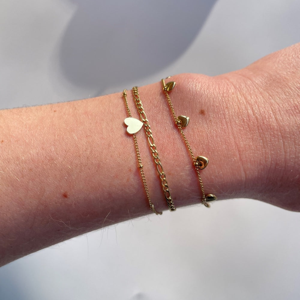 Dit goudkleurige armbandje bestaat uit twee fijne schakelarmbandjes. Het ene armbandje heeft een fijne schakel en het andere armbandje heeft een hartje in het midden. De armband is gemaakt van stainless steel, hierdoor verkleurt de armband niet. De armband is ook verkrijgbaar in het zilver en is te bestellen op www.jenelry.com
