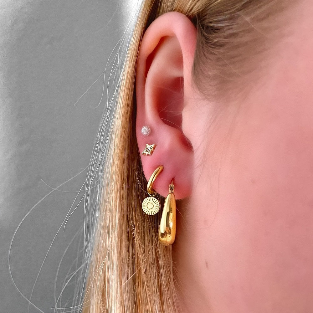Oorbellen Sunny Goud bestaan uit een oorringetje met een rond bedeltje. De oorbellen zijn eenvoudig te sluiten door het kliksysteem en hebben een rond bedeltje. De oorbellen zin waterproof, nikkelvrij en gemaakt van Stainless Steel. Hierdoor verkleuren de oorbellen niet en blijven ze lang mooi. De oorbellen zijn verkrijgbaar in het goud en zilver en zijn te bestellen op www.jenelry.com